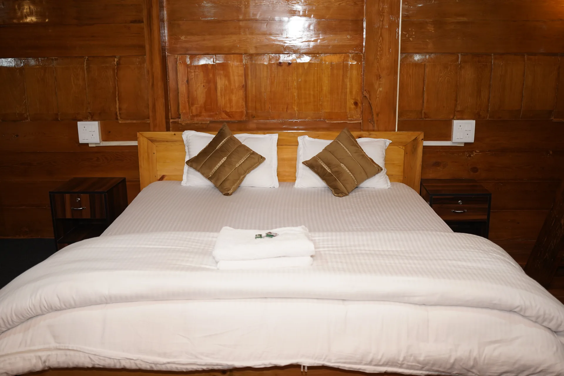 Bedroom with wooden headboard and golden pillows at Acorn Homestay