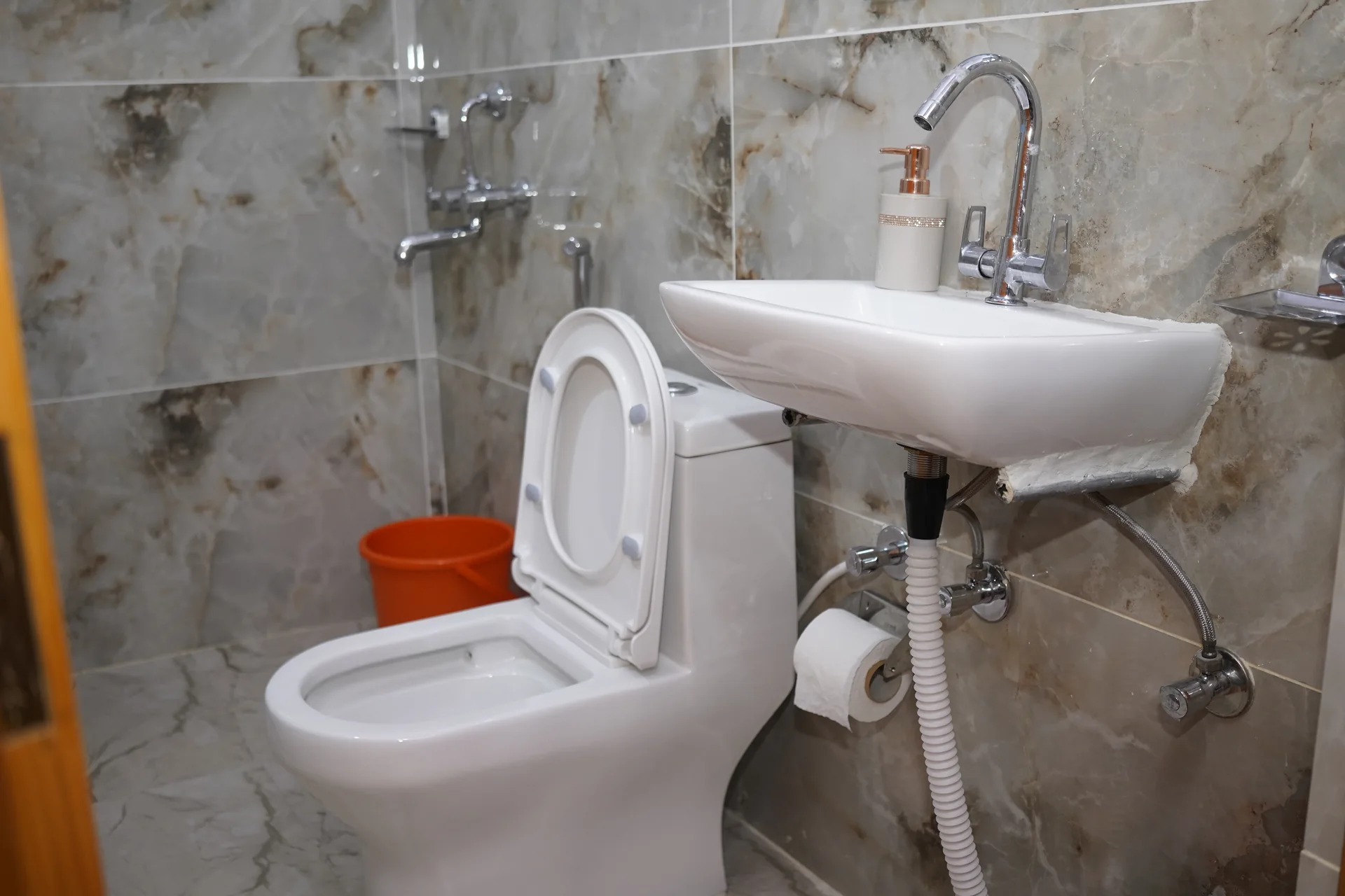 Clean attached bathroom with toilet and sink at Acorn Homestay