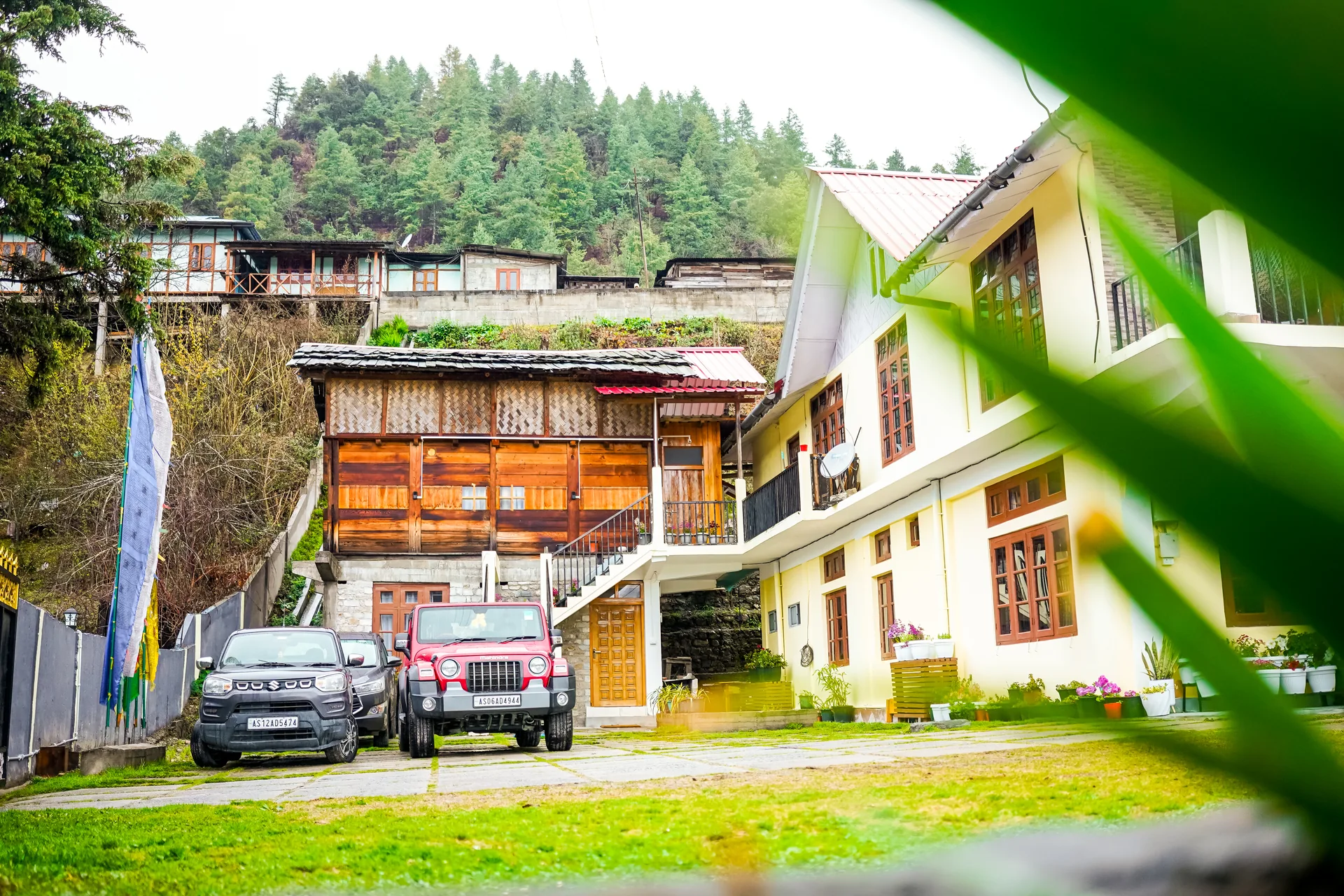 Acorn Homestay exterior with Jeeps parked in garden