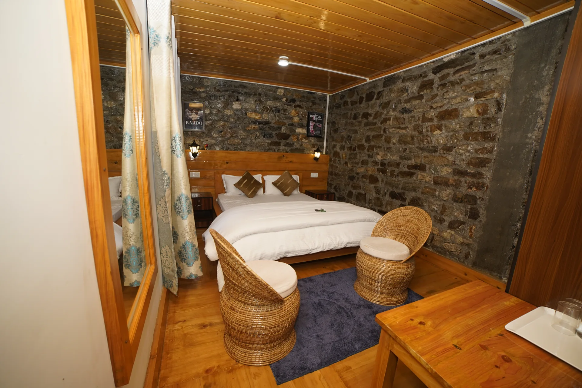 Cozy room with stone wall and wicker chairs at Acorn Homestay