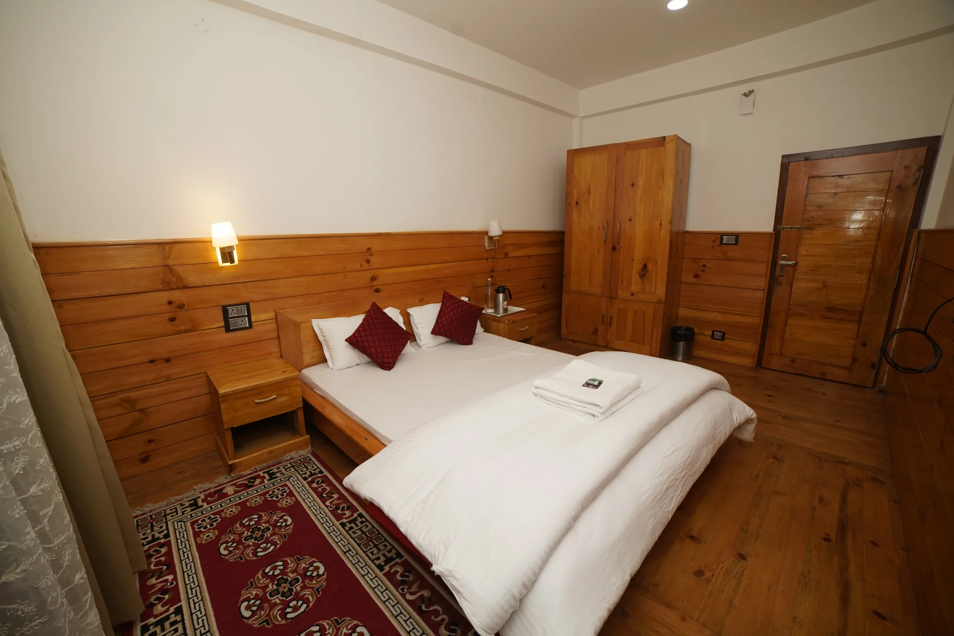 Wooden panel bedroom with red pillows at Acorn Homestay